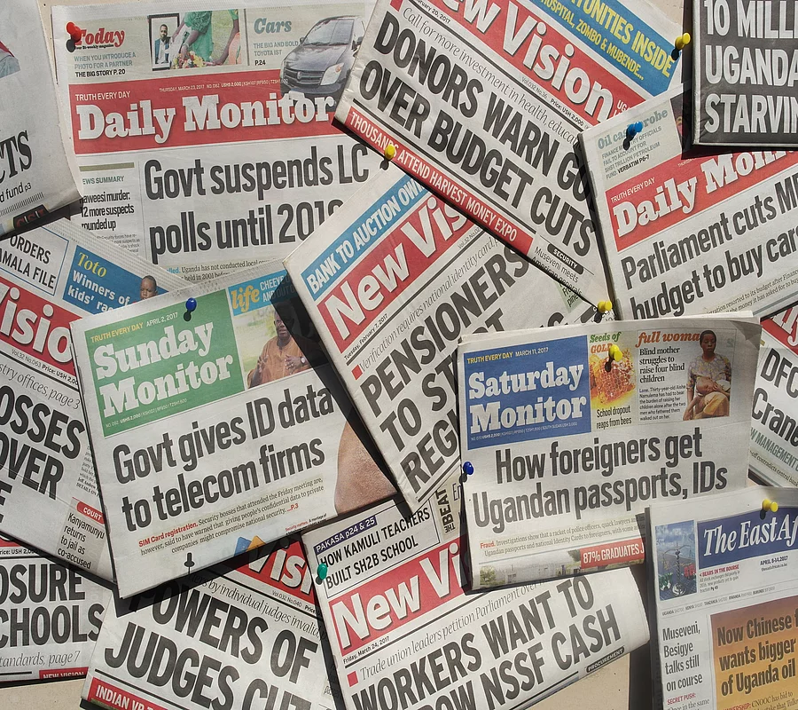 The picture shows a collection of Ugandan newspapers, including issues of the Daily Monitor and New Vision.