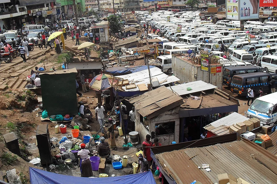 The photograph shows a bustling market scene in the centre of Kampala, Uganda.